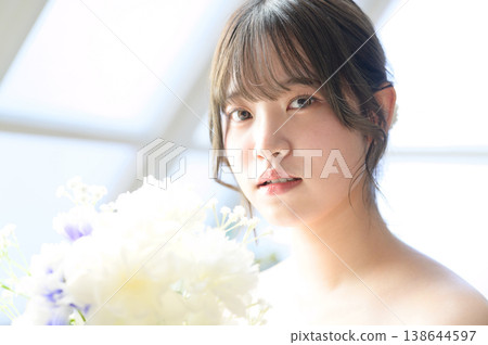 A Japanese woman smiling by the window, holding a bouquet. A Japanese woman smiling by the window, holding a bouquet. 138644597