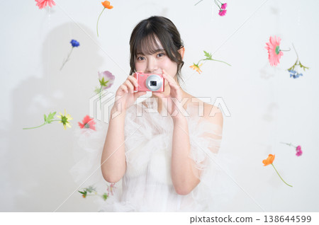 A Japanese woman in a wedding dress smiles while holding a compact digital camera. A Japanese woman in a wedding dress smiles while holding a compact digital camera. 138644599