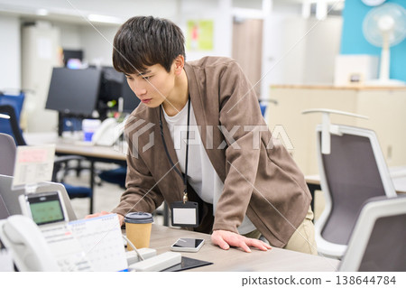 一名年輕的男員工站在一間空置的辦公室裡,查看他的筆記型電腦螢幕。 一名年輕的男員工站在一間空置的辦公室裡,查看他的筆記型電腦螢幕。 138644784