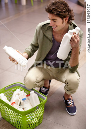 Man, milk and product comparison in grocery store, choice or shopping basket selection. Male person, smile and dairy drink for supermarket decision, expiry date information or reading nutrition value 138645087
