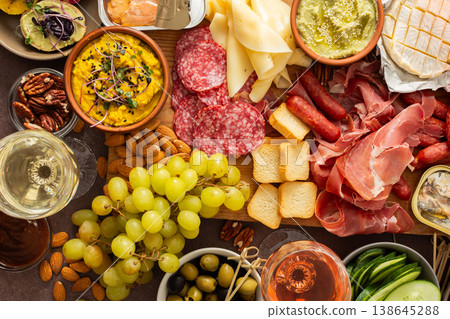 This festive spread features an array of cheese, cured meats, hummus, nuts, and fresh vegetables. Perfect for sharing at a casual get-together or celebration with friends This festive spread features an array of cheese, cured meats, hummus, nuts, and fresh vegetables. Perfect for sharing at a casual get-together or celebration with friends 138645288