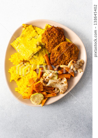 A vibrant plate features fluffy yellow rice, creamy rhubarb fried eggs, and crispy meat fritters, showcasing a hearty and flavorful meal perfect for any time of the day 138645402