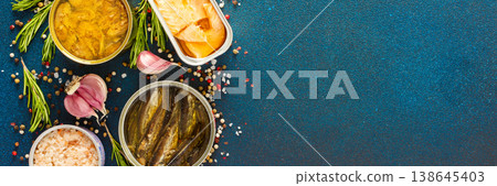 Different open tin cans with canned fish like salmon, mackerel, sprat, sardine, shrimp, among spices and herbs on a blue background, viewed from the top, banner Different open tin cans with canned fish like salmon, mackerel, sprat, sardine, shrimp, among spices and herbs on a blue background, viewed from the top, banner 138645403