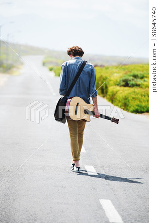 Musician, walking and man with a guitar on a road trip, journey or tour in the countryside on highway. Guitarist, travel or back of guy trekking on street or asphalt in a green and rural landscape Musician, walking and man with a guitar on a road trip, journey or tour in the countryside on highway. Guitarist, travel or back of guy trekking on street or asphalt in a green and rural landscape 138645740