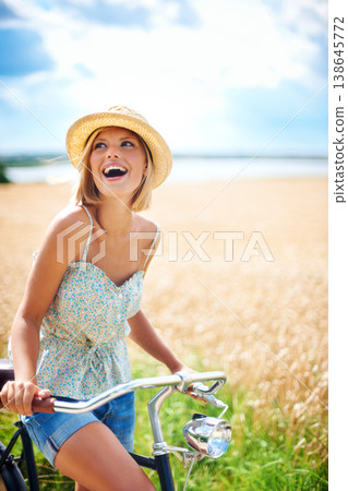 Woman laughing on bicycle in the countryside, happiness and travel on journey or thinking outdoor. Funny, bike and excited person smile at field on transport, freedom and cycling in nature in summer 138645772