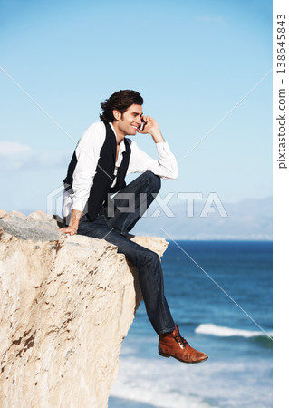 Cliff, edge and man with a happy phone call at the ocean, beach or connection on vacation, travel or social media. Businessman, contact and edgy chat on cellphone, communication or talking above sea Cliff, edge and man with a happy phone call at the ocean, beach or connection on vacation, travel or social media. Businessman, contact and edgy chat on cellphone, communication or talking above sea 138645843