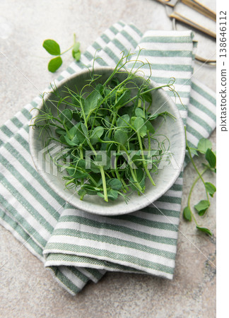 Fresh green pea shoots in bowl with striped cloth 138646112