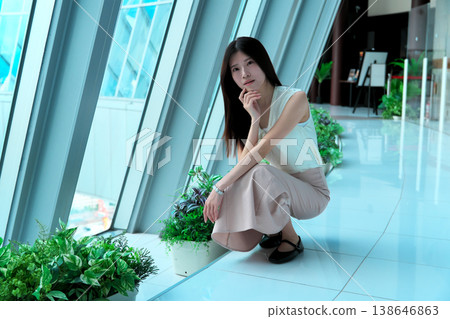 一位身穿無袖連身裙的年輕女子蹲下身子,轉過身來。 一位身穿無袖連身裙的年輕女子蹲下身子,轉過身來。 138646863