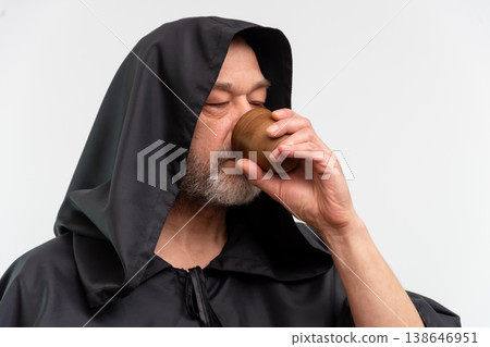 Bearded monk with hood drinking beverage on white background isolated Bearded monk with hood drinking beverage on white background isolated 138646951