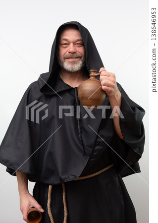 Male monk in black robe holding clay jug 138646953