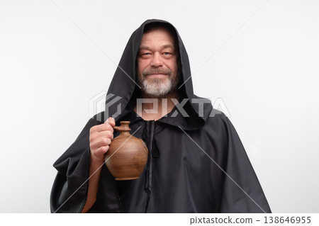 Male monk standing holding clay jug wearing black robe 138646955