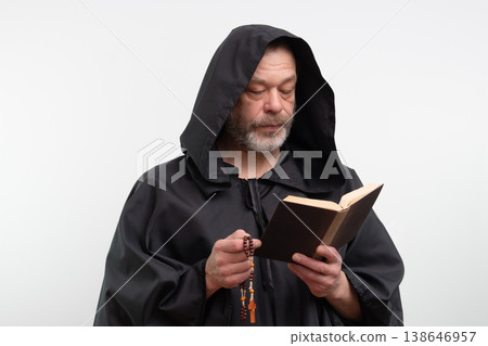 Bearded monk wearing hood holding book and rosary on white background. 138646957