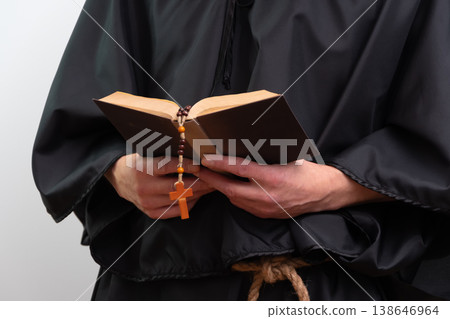 Close up of monk hands holding book and rosary isolated. 138646964