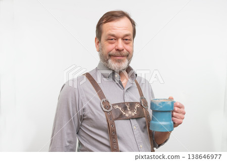 Bearded man wearing Bavarian traditional outfit posing with ceramic beer mug in studio. 138646977