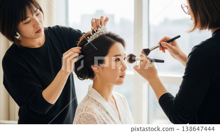 Wedding - Asian Bride Getting Tiara and Makeup Done by Two Professional Stylists in Bright Bridal Room 138647444