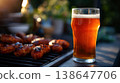Cold glass of draft beer and grilled sausages in backyard open space, grill party setup, summer entertaining, outdoor cooking, patio lifestyle, golden hour lighting. 138647706
