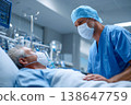 male doctor in blue scrubs and a medical cap leaning over a patient in a hospital bed. 138647759