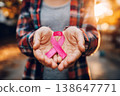 woman holding pink cancer awareness ribbon in warm sunlight background. 138647771