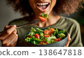 A woman holding a bowl of salad with her mouth open, 138647818