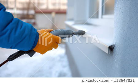 Worker is cleaning a concrete driveway with a pressure washer. 138647821