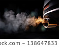 Extreme close-up of car exhaust releasing thick dark smoke into the air, smoke forming soft layered curls in slow motion, reflective chrome tip showing highlights and grime, engine. 138647833
