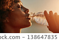 close up Woman drinks water from a plastic bottle in warm sunlight . 138647835
