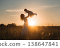 mother raising baby girl up high on a beautiful sunset . 138647841