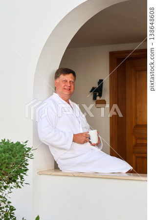A man on vacation sits in a robe and drinks coffee A man on vacation sits in a robe and drinks coffee 138648608