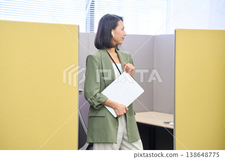 一位女商人站在私人辦公隔間前，面前放著一台筆記型電腦。 138648775