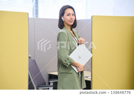 一位女商人站在私人辦公隔間前,面前放著一台筆記型電腦。 一位女商人站在私人辦公隔間前,面前放著一台筆記型電腦。 138648776