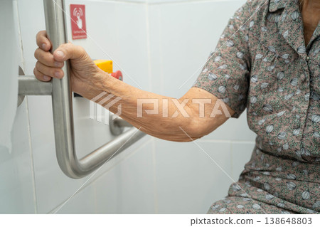 Asian elderly woman use toilet security support rail in bathroom. Asian elderly woman use toilet security support rail in bathroom. 138648803