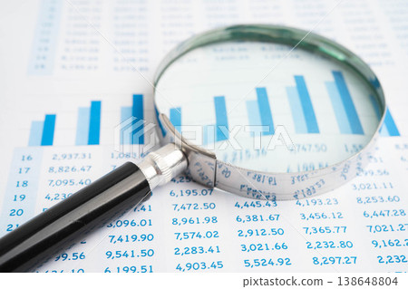 Magnifying glass on data business graphs paper. Magnifying glass on data business graphs paper. 138648804