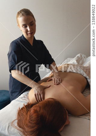 Therapist giving a professional back massage to a client, providing relaxation, wellness, and stress relief in a spa or clinic Therapist giving a professional back massage to a client, providing relaxation, wellness, and stress relief in a spa or clinic 138649022