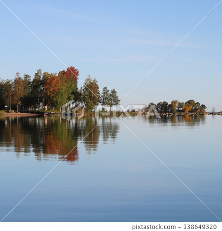 Colorful trees in Vita Sannar mirroring in Lake Vanern, autumn day in Sweden. Colorful trees in Vita Sannar mirroring in Lake Vanern, autumn day in Sweden. 138649320