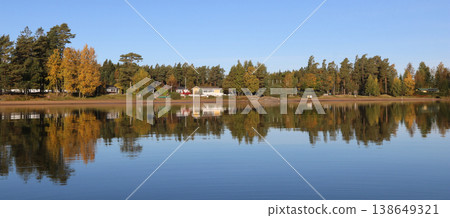 Golden autumn trees in Vita Sannar mirroring in Lake Vanern, Sweden. Golden autumn trees in Vita Sannar mirroring in Lake Vanern, Sweden. 138649321