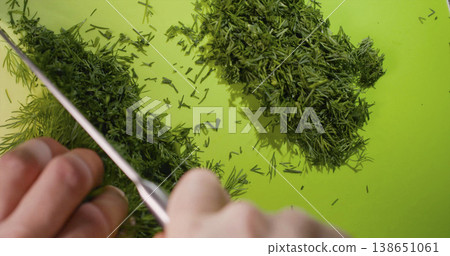 Chopping fresh dill on a cutting board in a kitchen during daylight hours Chopping fresh dill on a cutting board in a kitchen during daylight hours 138651061
