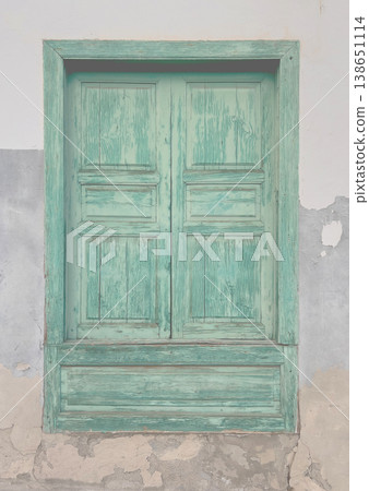 Weathered green wooden window shutters peeling paint 138651114