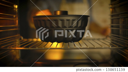 Black cooking pot sits on a rack inside an oven with warm light shining through Black cooking pot sits on a rack inside an oven with warm light shining through 138651139
