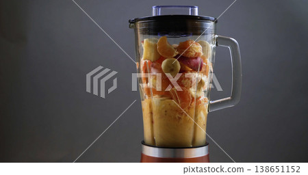 Making a fruit smoothie in a blender with mixed fruits like bananas, oranges, and apples during the day Making a fruit smoothie in a blender with mixed fruits like bananas, oranges, and apples during the day 138651152
