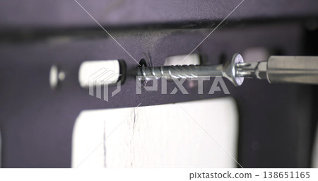 Screw being fastened into a wall using a drill bit during home improvement project in a room Screw being fastened into a wall using a drill bit during home improvement project in a room 138651165