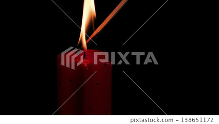 Candle flame burns brightly while a match ignites it in a dark setting during the evening Candle flame burns brightly while a match ignites it in a dark setting during the evening 138651172