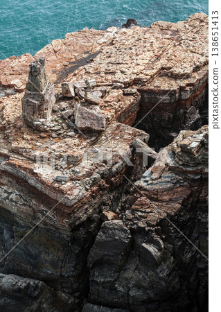 A stunning rocky cliff formation rising against the background of the blue ocean A stunning rocky cliff formation rising against the background of the blue ocean 138651413