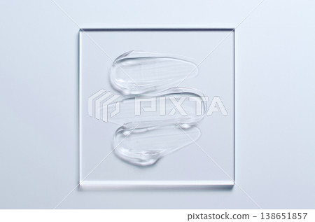 A sample of a transparent cosmetic skin care product on glass. Blue background A sample of a transparent cosmetic skin care product on glass. Blue background 138651857