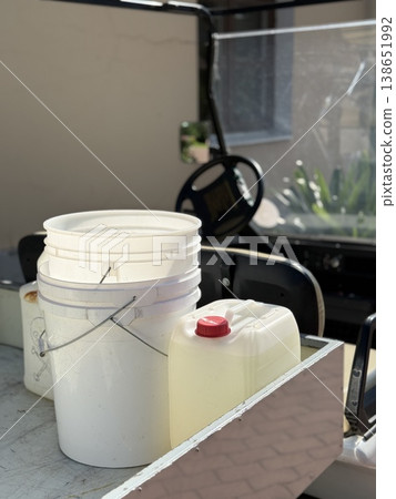 White plastic bucket and jug on utility vehicle. Outdoor maintenance concept with background White plastic bucket and jug on utility vehicle. Outdoor maintenance concept with background 138651992