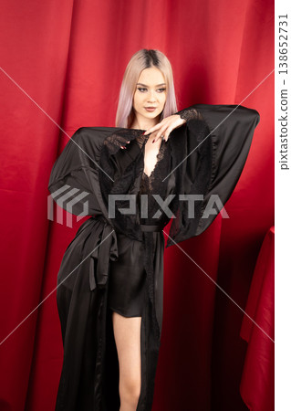 Elegant woman in black robe posing against red wall 138652731