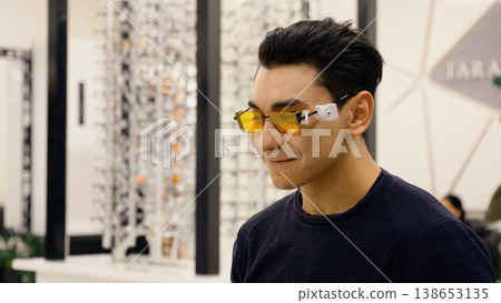 Man wearing yellow tinted sunglasses in optical shop Man wearing yellow tinted sunglasses in optical shop 138653135
