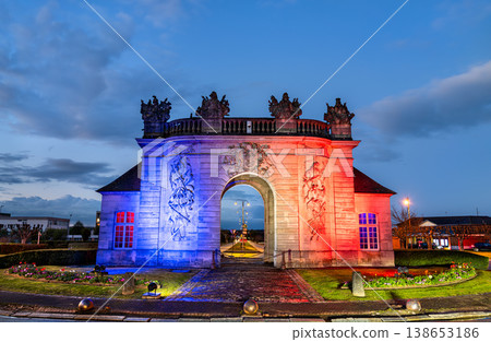 The historic Porte du Pont stone gateway illuminated with the colors of the French flag at dusk in Vitry-le-Francois, France. 138653186