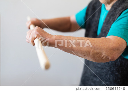 Senior woman exercising with stick for rehabilitation Senior woman exercising with stick for rehabilitation 138653248