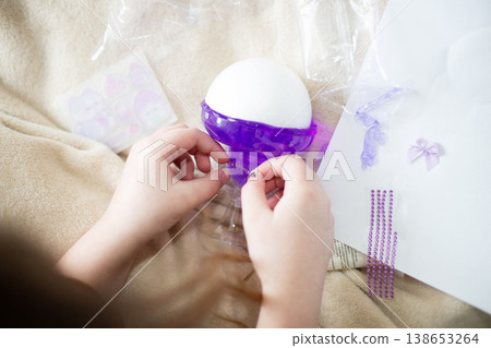 Child hands decorating purple toy with rhinestones 138653264