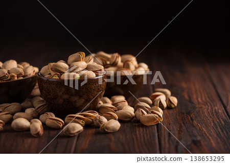 Pistachios in Rustic Ceramic Bowls on Dark Wooden Background 138653295